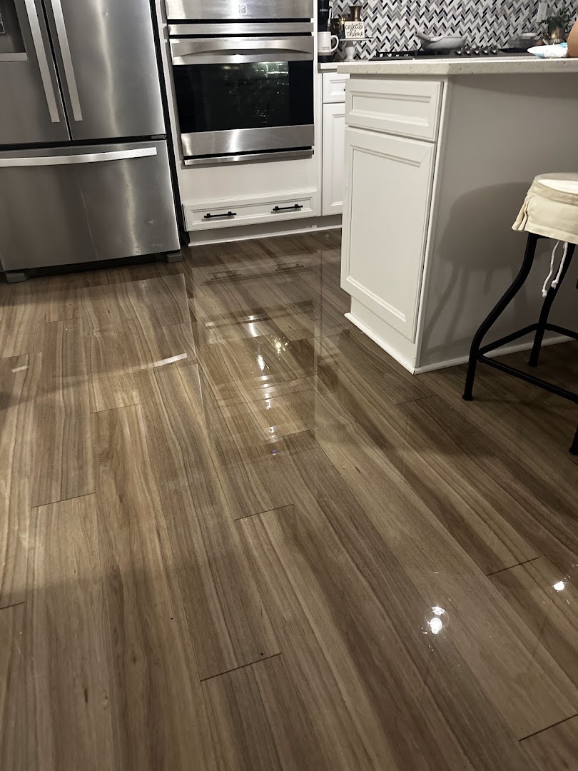 Water pooled across a wood kitchen floor in front of stainless appliances