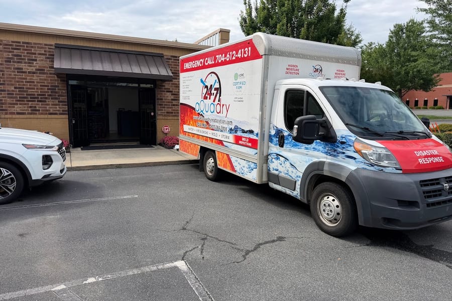 A branded 24-7 AquaDry box truck parked outside a commercial building