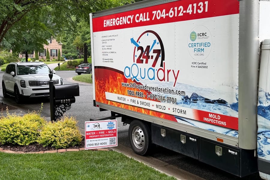 A branded 24-7 AquaDry box truck parked curbside